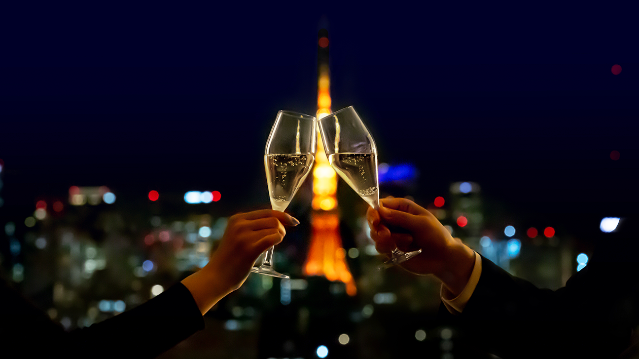 大切な人と二人で東京タワーの夜景をバックに、シャンパンで乾杯している。