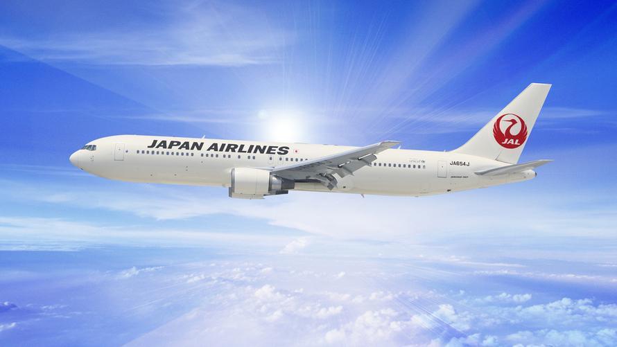 美しい青空を背景に飛行するJAL旅客機のイメージ。