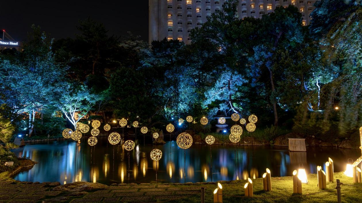 夜の日本庭園の池に浮かぶ竹まりが灯っている。